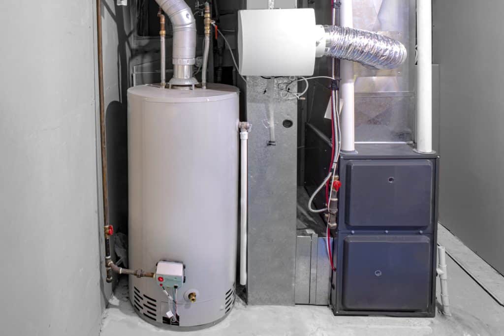 Indoor HVAC system featuring a gas furnace, cylindrical water heater, ventilation ducts, and connected plumbing in a utility room.